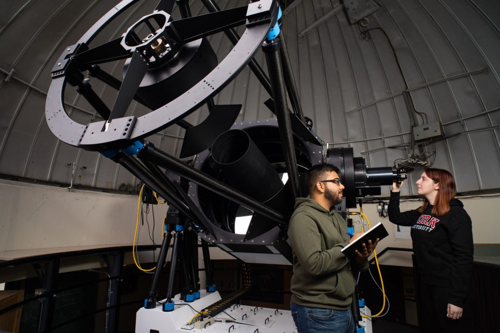 two students working by a telescope