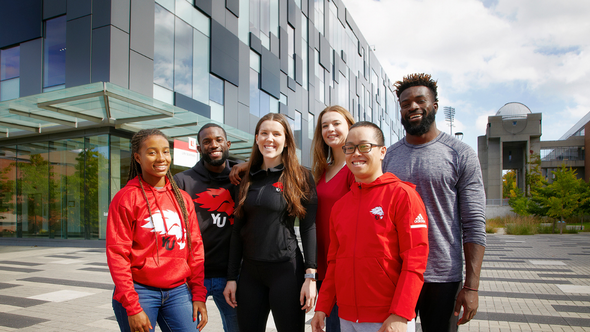 Diversity group of students standing outside The Life Sciences building wearing York gear